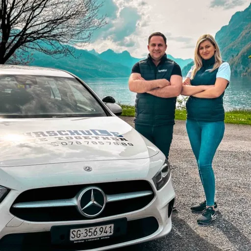 Atila Fetai und Besarta Fetai stehen hinter dem Mercedes von Drive Together Fahrschule